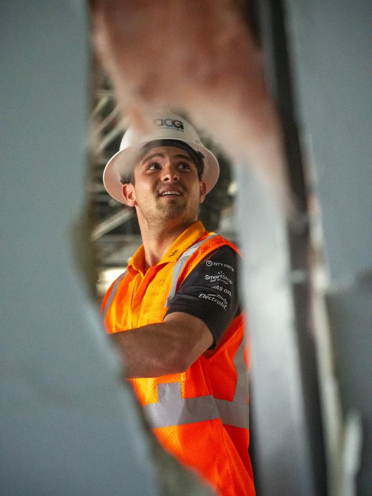 A subcontractor in a hard hat and hi-vis vest looking up on site